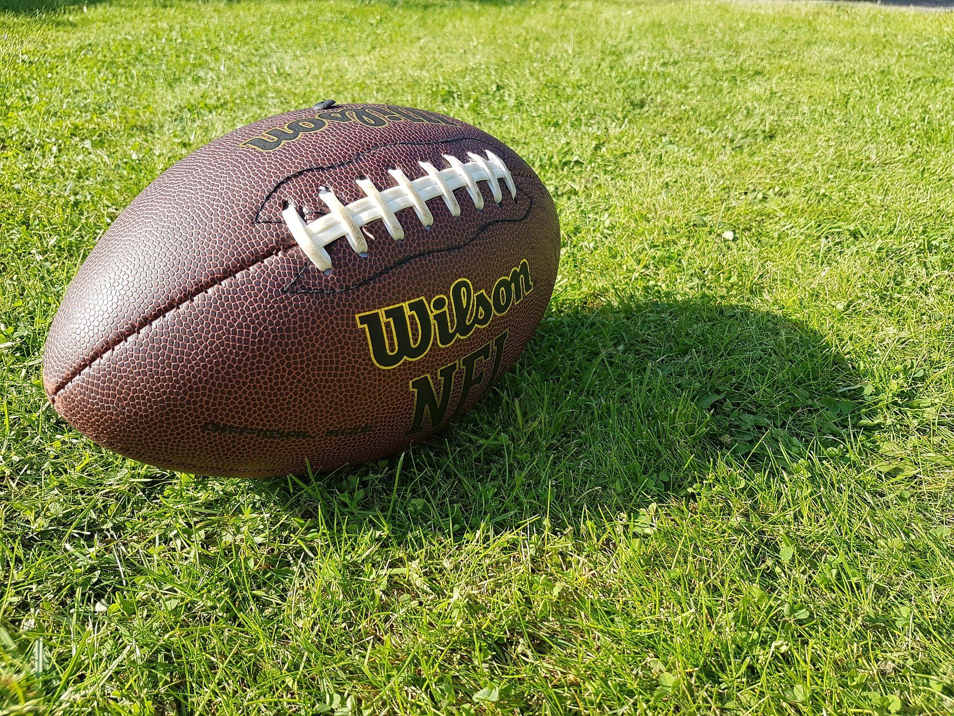 A football lays on a turf field. 