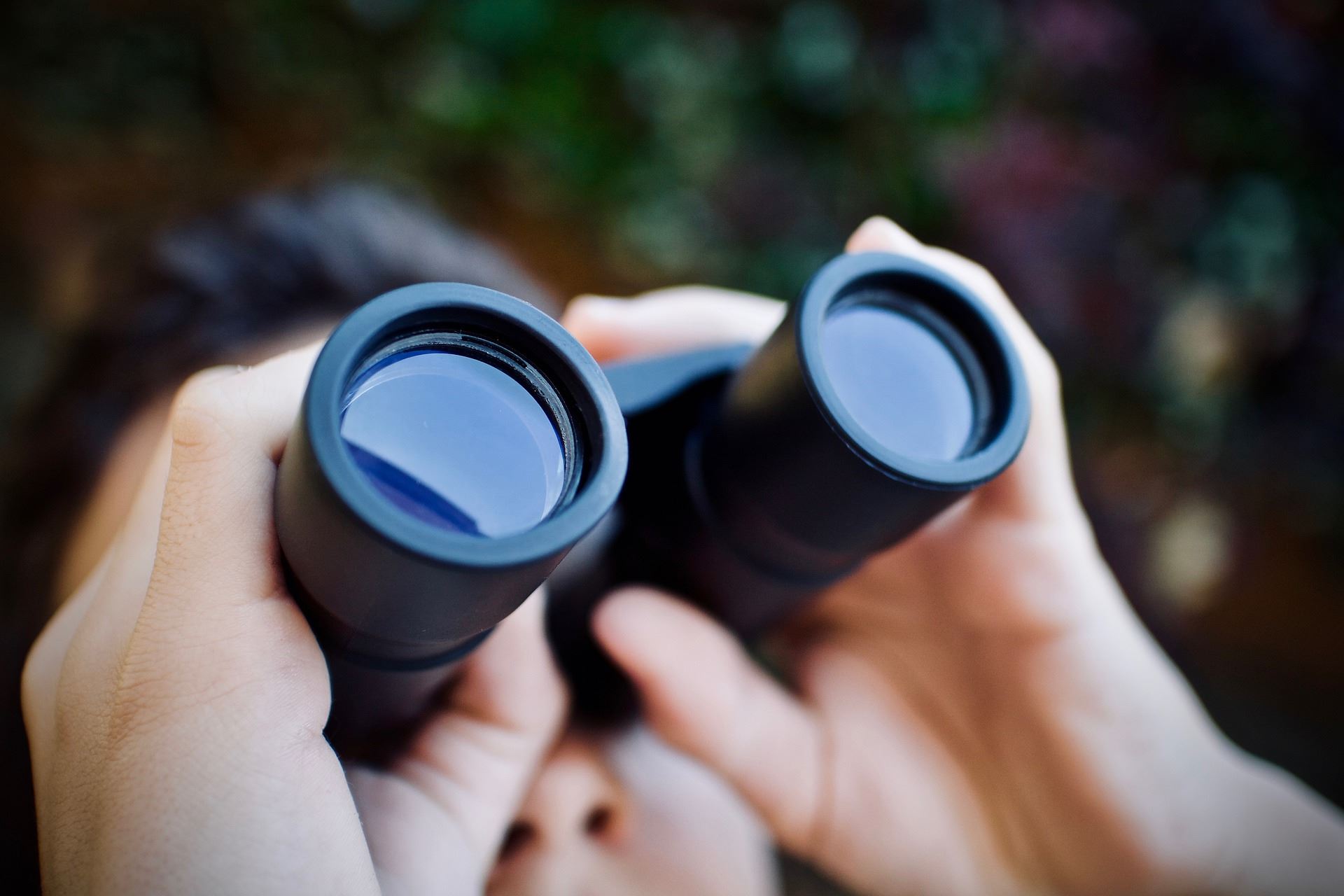 A person holds a pair of binoculars.
